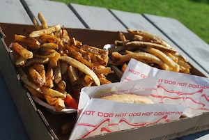 Fries with burgers and ketchup on a picnic table.