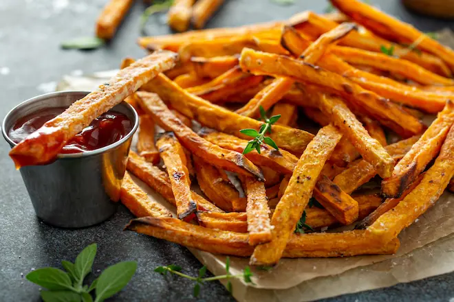 Sweet potato fries with ketchup and mayo, one fry dipped in ketchup.